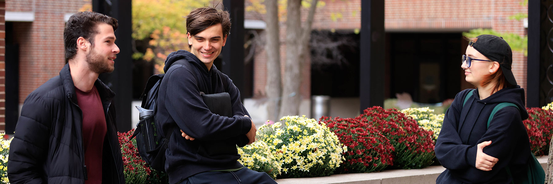 three students conversing on campus
