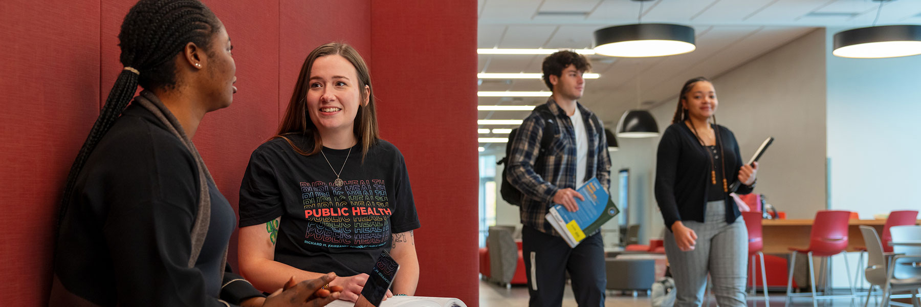 two public health students talking while two other students walk by in health sciences building