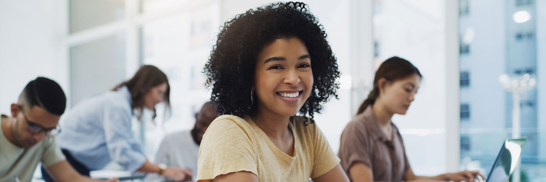 woman sitting at desk in classroom smiling