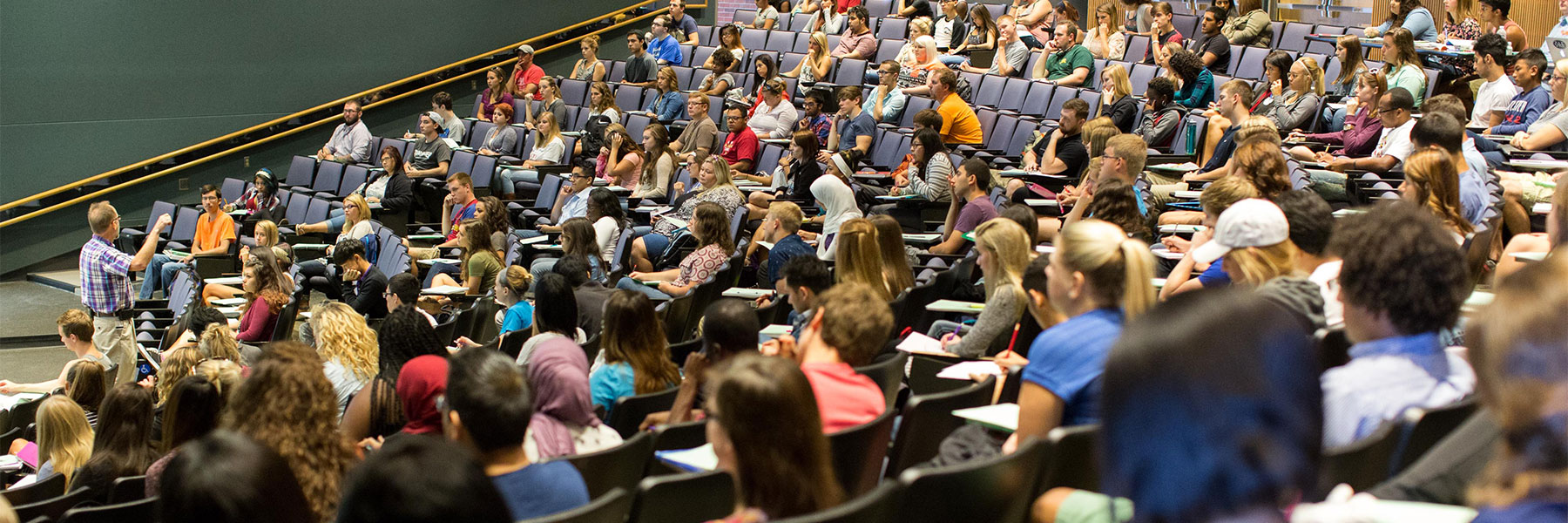 Students listen to instructor in large classroom