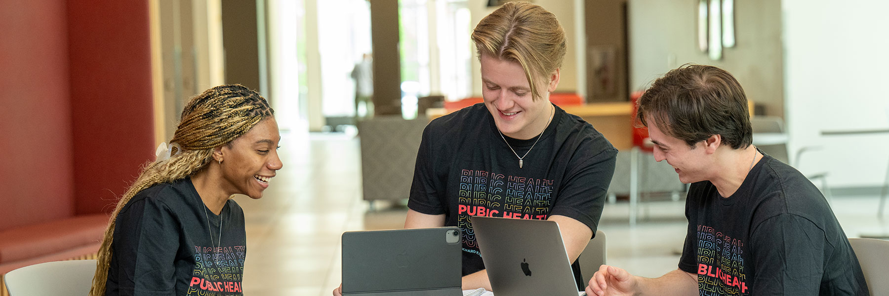 3 public health students laughing and looking at laptops