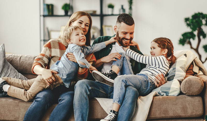 mother and father each holding a child in their lap on a couch